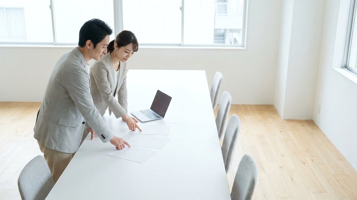 明るい会議室で、印刷した資料を指しながら広告の成果を話し合う2人