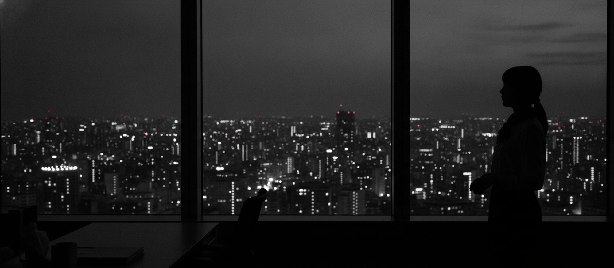 夕暮れの都市を窓から見渡す人物