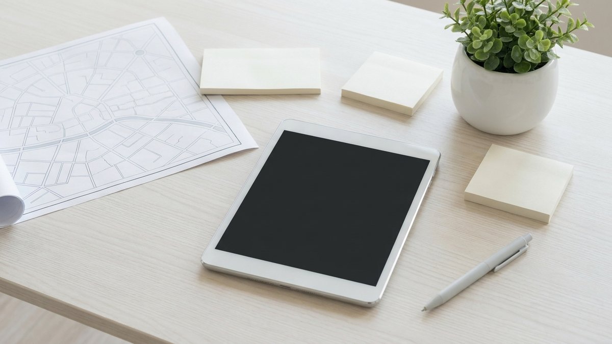 木目のデスクの上に、地図、付せん、タブレット、ペンが並び、テレビCMの出稿エリアを検討している様子